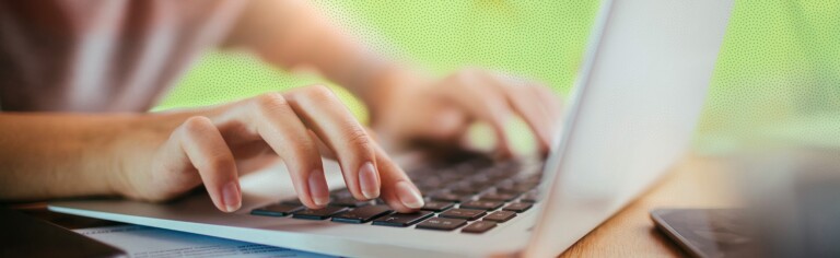 close up of hands typing on laptop