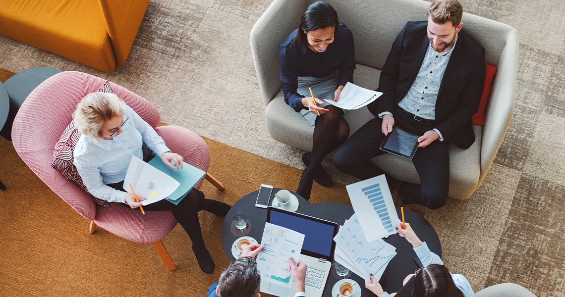 Aerial view of business colleagues reviewing data reports in casual setting.