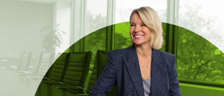Kim Fahey sitting at a desk smiling and looking to the left