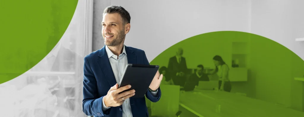 Professional leaning against a wall in an office holding an tablet