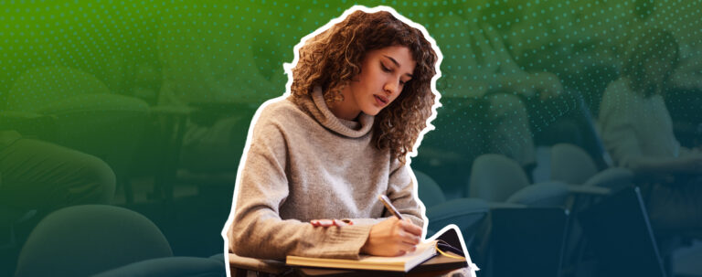 College student writing notes while studying for class.
